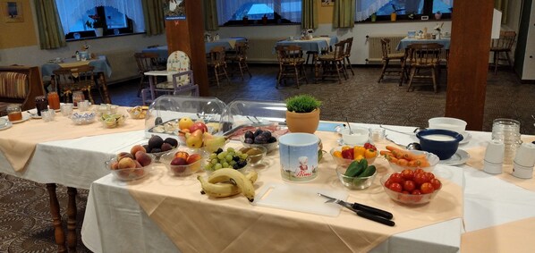 Una mesa de buffet con varias frutas y verduras, una tabla de cortar y un cuchillo.