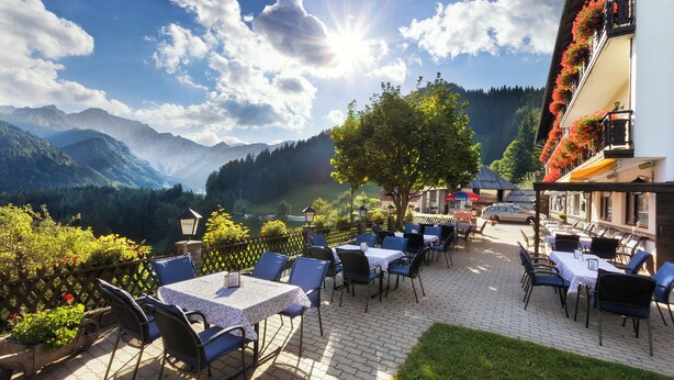 An outdoor patio with tables and chairs, overlooking a mountainous landscape. - Bed&Breakfast Lausegger (Ferlach)