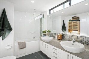 Features a double sink, standalone bathtub, and toilet in a sleek, minimalist design.