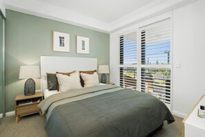 Relax in this serene bedroom with a large bed, bedside tables, and a window offering a view of the outdoors.