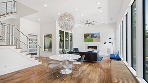 Ein modernes Interieur mit Essbereich, Treppe und großen Fenstern.