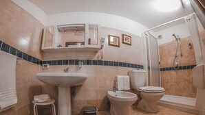 Un baño con lavamanos, bidé, inodoro y ducha.