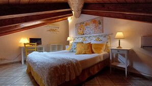 Un dormitorio acogedor con una cama, dos mesitas de noche con lámparas, un televisor y un cuadro en la pared.