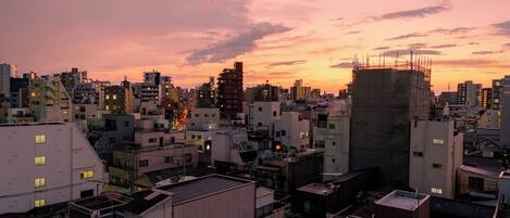 A cityscape at sunset with various buildings, including a construction site with scaffolding.