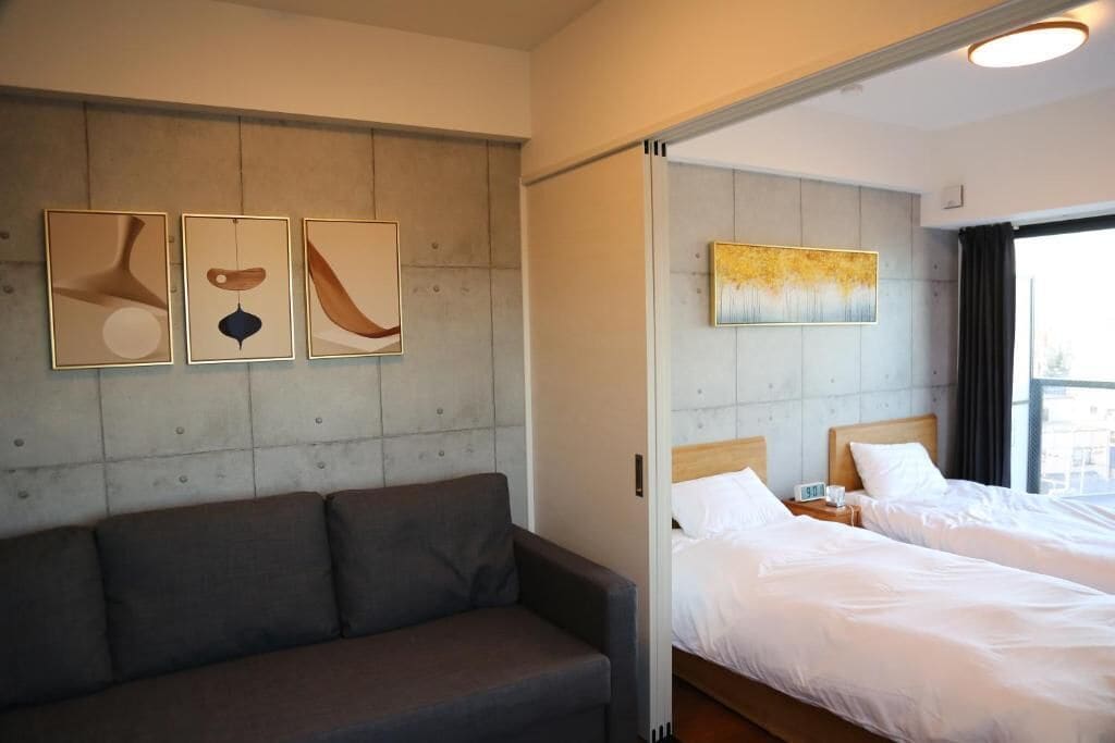 Habitación de hotel con sofá, dos camas, una mesita de noche y arte abstracto en la pared.