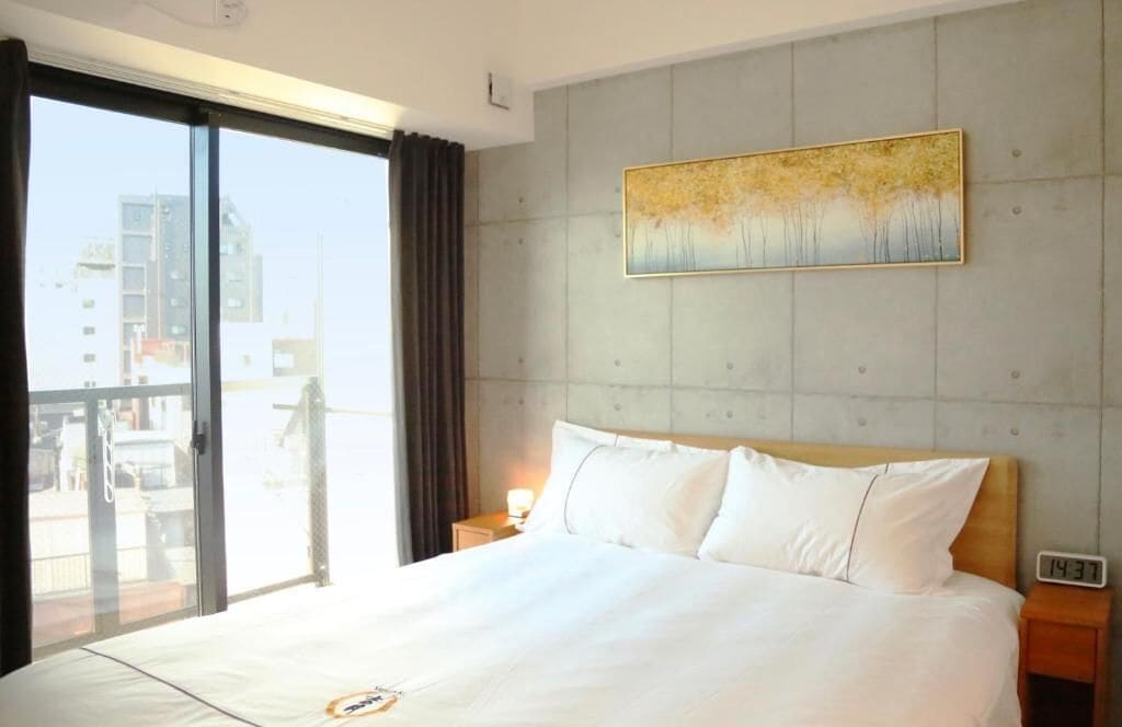 Habitación de hotel con una cama grande, una mesita de noche, un reloj y un cuadro en la pared.
