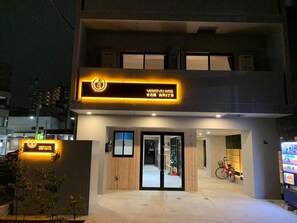 The exterior of Yoshioka Hotel with a modern design, featuring a prominent entrance with glass doors and a neon sign. - Yoshitsuki Hotel (Tokyo)