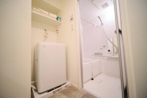 A small, white bathroom with a toilet, a shower, and a built-in sink. - Yoshitsuki Hotel (Tokyo)