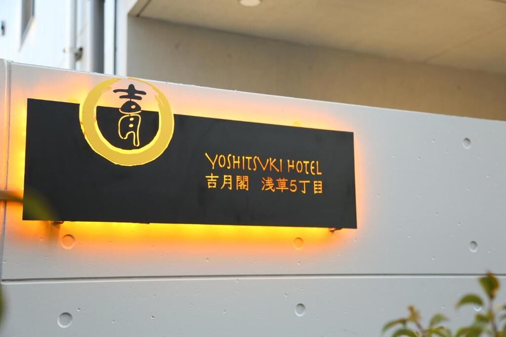 A hotel sign with the name 'Yoshitsuki Hotel' and Japanese text indicating its location.