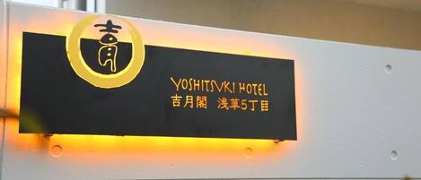 A hotel sign with the name 'Yoshitsuki Hotel' and Japanese text indicating its location.