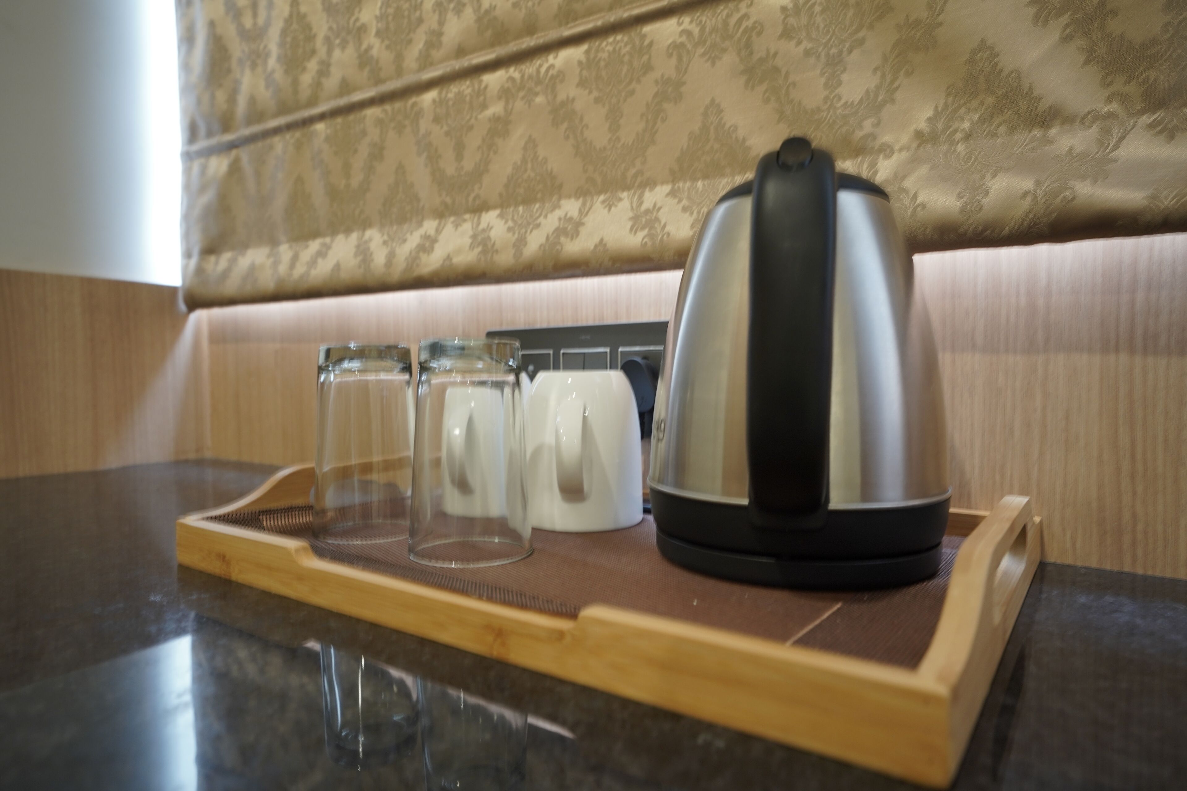 Un comptoir de cuisine avec une bouilloire, une machine à café et deux verres disposés sur un plateau.