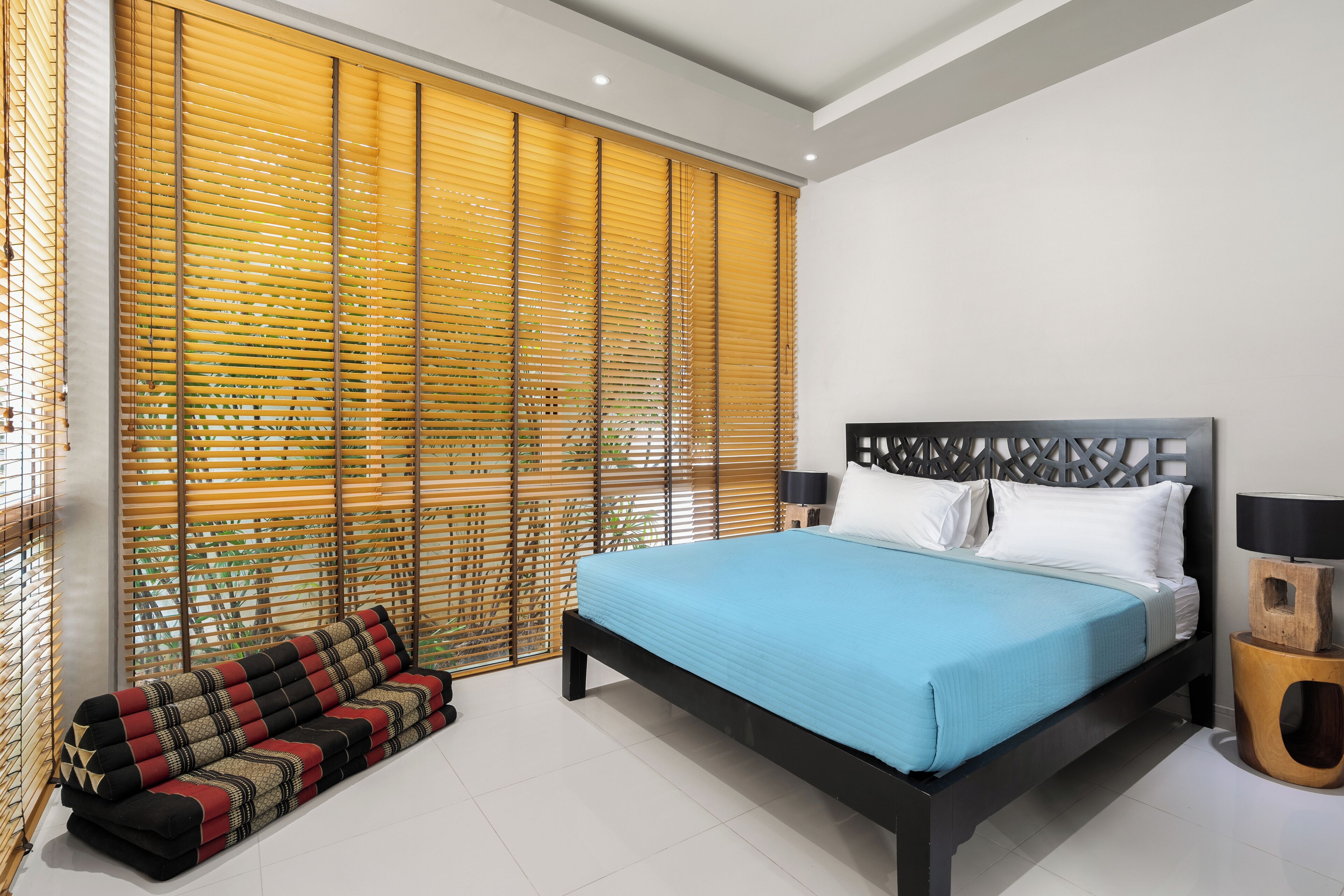 A modern bedroom with a large bed, a sofa, and a decorative wall panel.