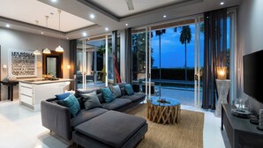 A modern living room with a grey sectional sofa, a round coffee table, and a TV on a stand.
