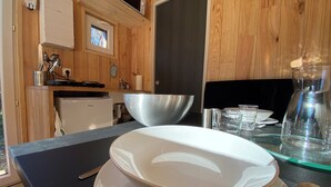 A kitchen with wooden cabinets, a microwave, a stove, and a large metal bowl on the counter. - Lescargoterie de la Forge - Immersion Champêtre (Uzemain)
