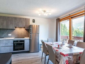 Una cocina moderna con horno Bosch, refrigerador de acero inoxidable y un comedor con mesa para dos.