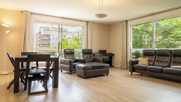 Un ampio soggiorno con zona pranzo, ampie finestre e una moderna lampada a soffitto.
