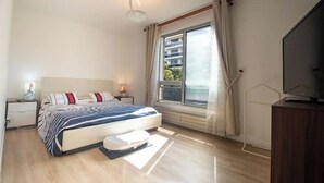 Una camera da letto moderna con un letto, comodini, una televisione e una finestra con tende.