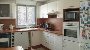 Una cucina compatta con mobili bianchi, un forno a microonde, un fornello e un frigorifero.