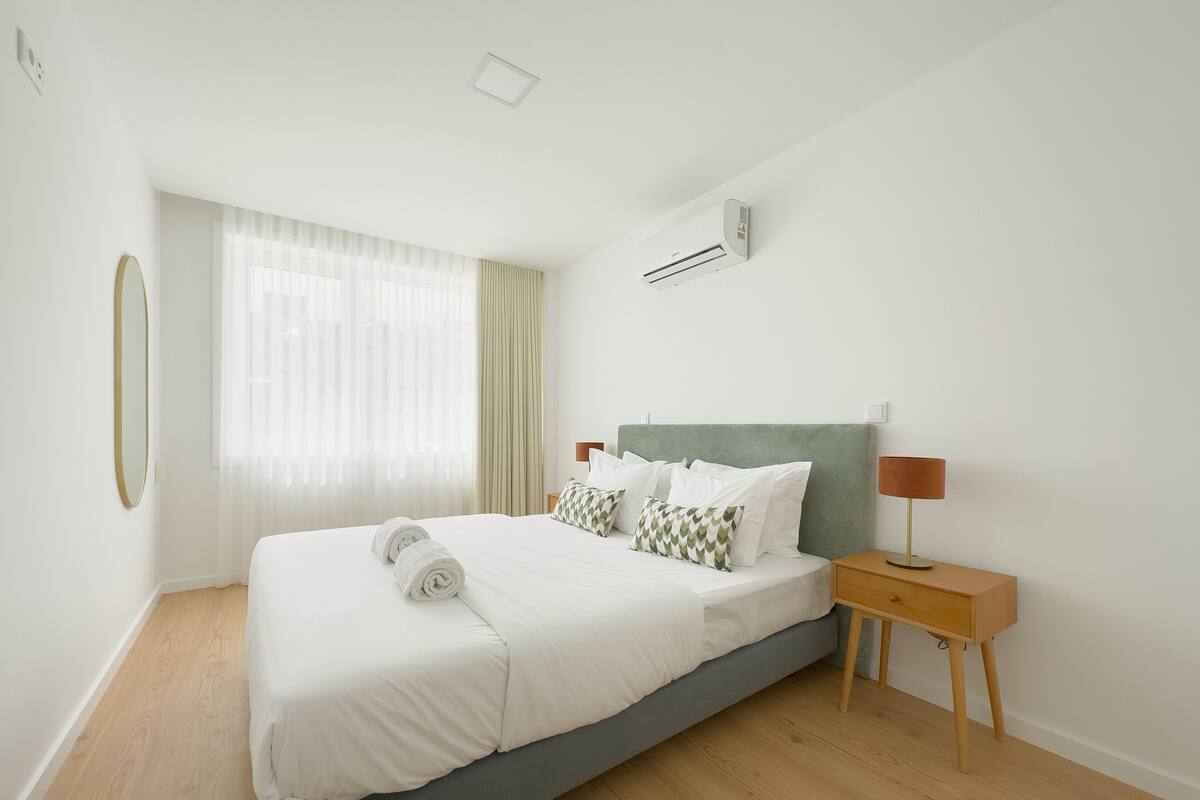 Une chambre d’hôtel moderne avec un grand lit, une table de chevet, une lampe et un appareil de climatisation.