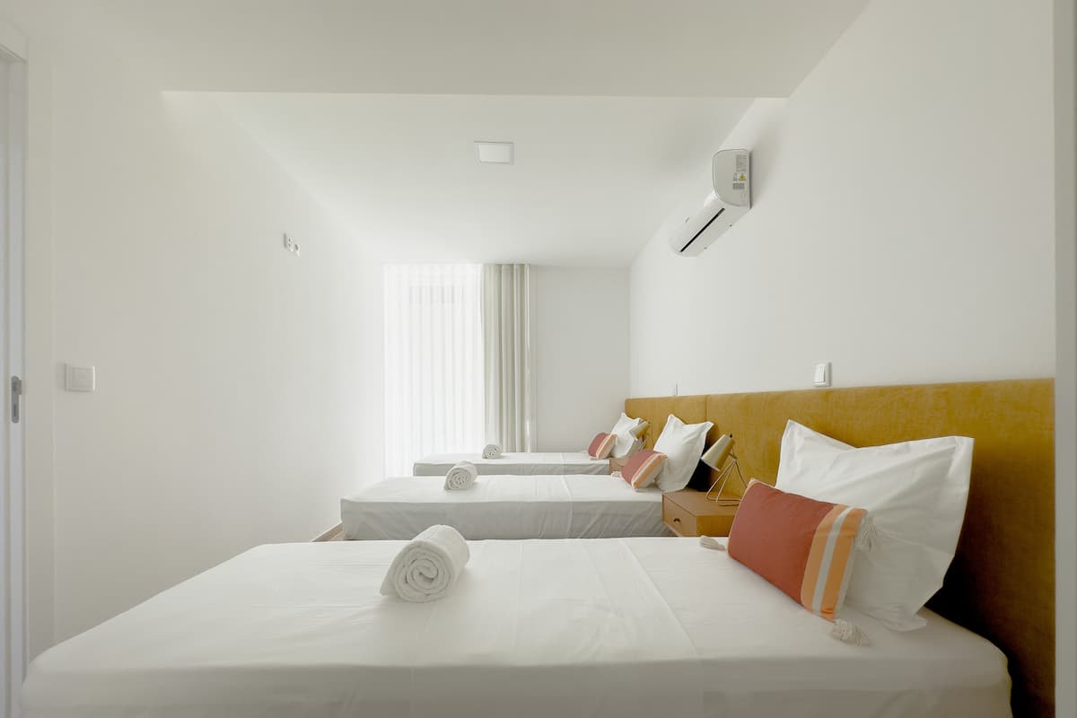 Habitación de hotel con dos camas, una mesita de noche, un espejo y aire acondicionado instalado en la pared.