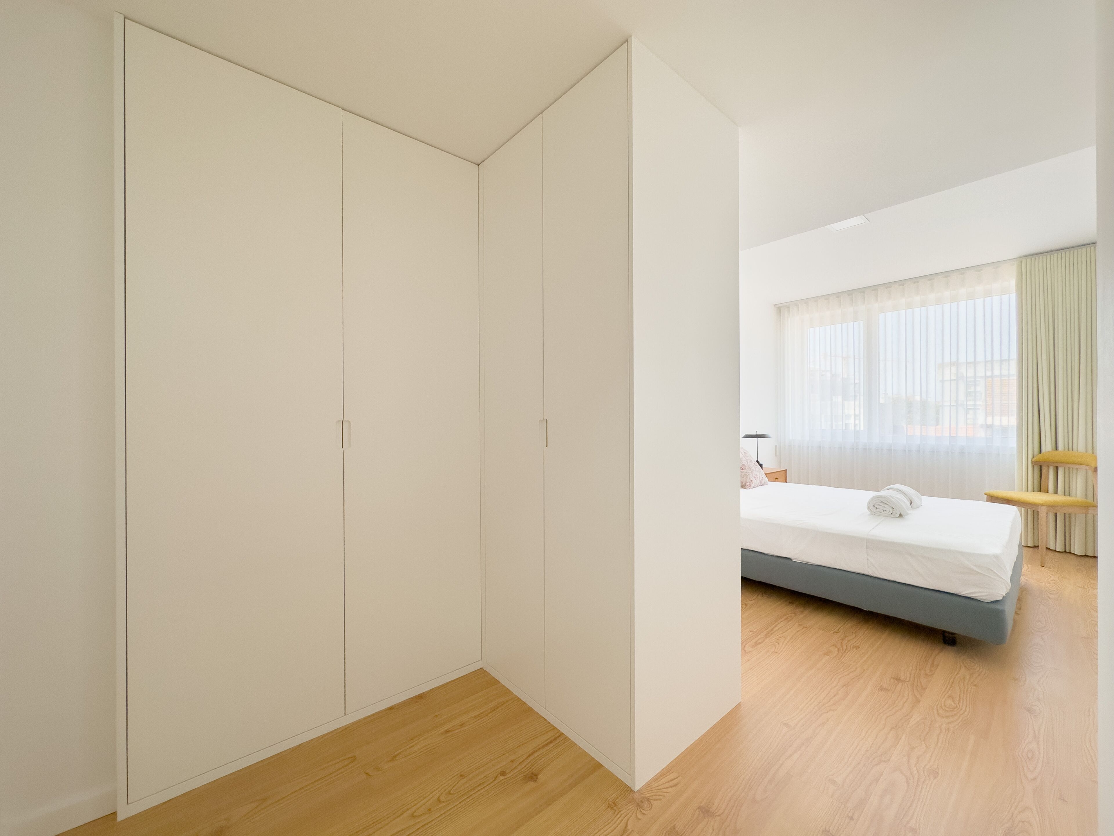 A bedroom with a bed, a wardrobe, and a window with curtains.