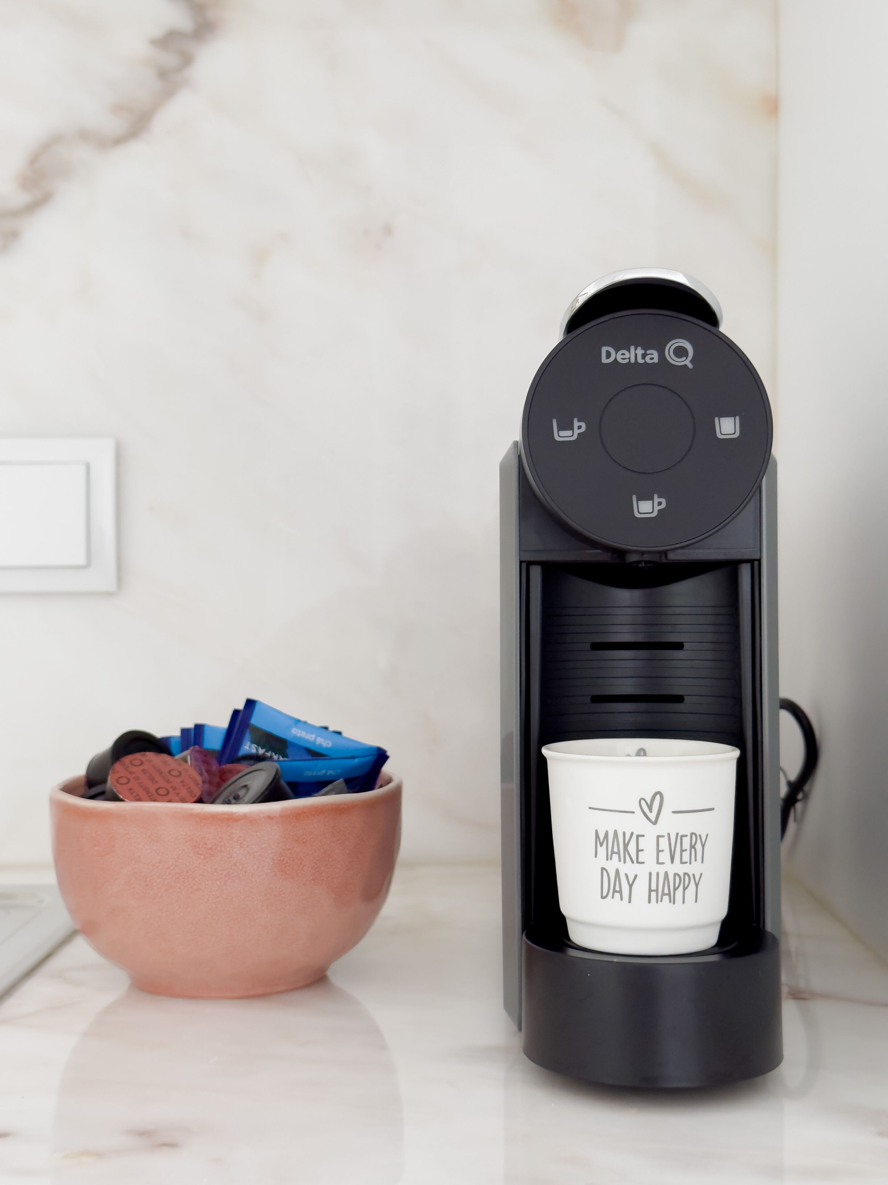 A coffee maker with a cup holder and a bowl of items.