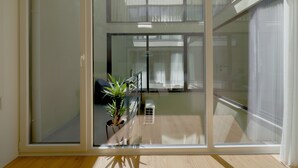 A room with a sliding glass door leading to a balcony, a potted plant, and a wooden floor. - Vibrant Host-Campo 24  (Porto)