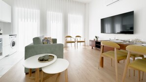 A modern living room with a sofa, dining table, chairs, and a TV. - Vibrant Host-Campo 24  (Porto)