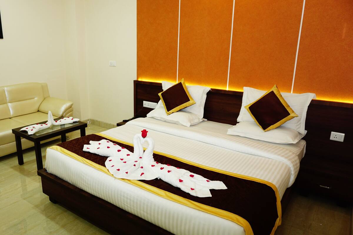 Quarto de hotel com cama, sofá e uma pequena mesa.