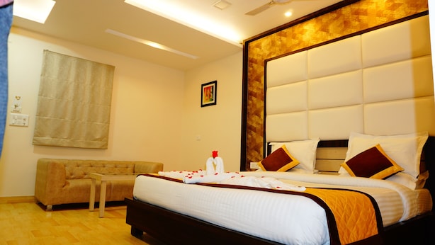 Quarto de hotel com uma cama grande, um sofá e uma mesa pequena.