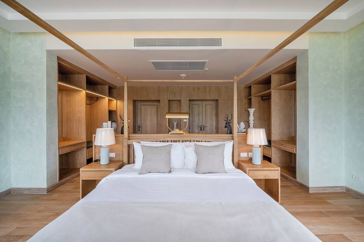 A spacious bedroom with a large bed, wooden headboard, and built-in shelving on either side.