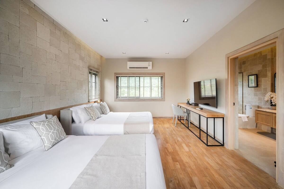A modern bedroom with a large bed, a desk, and a TV.