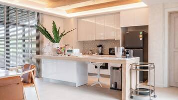 A modern kitchen with a central island, white cabinetry, and a stainless steel refrigerator.