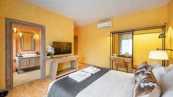 Une chambre d’hôtel comprenant un lit, un bureau avec une télévision, un miroir et une salle de bain avec un lavabo et une douche.