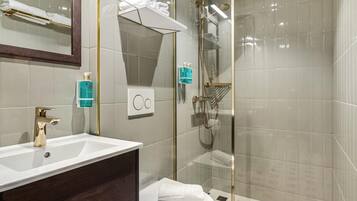 Une salle de bain moderne avec un lavabo blanc, un robinet doré et une cabine de douche en verre.