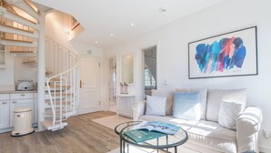 Ein modernes Wohnzimmer mit Treppe, einem weißen Sofa und einem Couchtisch.
