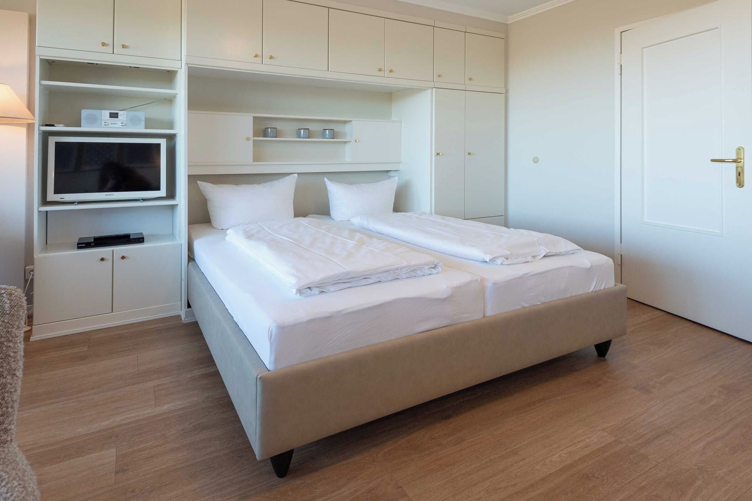 Un dormitorio con una cama, un televisor y armarios empotrados.