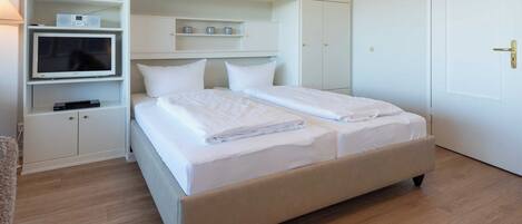 Un dormitorio con una cama, un televisor y armarios empotrados.