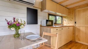Una cocina compacta con microondas, lavamanos y armarios de madera.