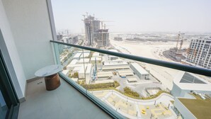 A balcony with a glass railing overlooking a construction site with several high-rise buildings under construction. - Yogi - Bright Apartment With Panoramic CityScape Views (Dubai)