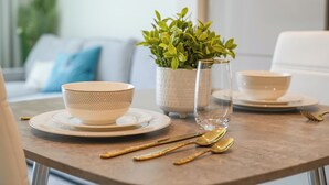 A dining table with a white bowl, a clear glass, and a potted plant. - Yogi - Bright Apartment With Panoramic CityScape Views (Dubai)