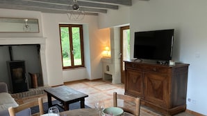 Een gezellige woonkamer met een open haard, een televisie en een eethoek, compleet met borden en glazen.