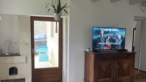 Een woonkamer met een televisie, een houten kast en een open haard.