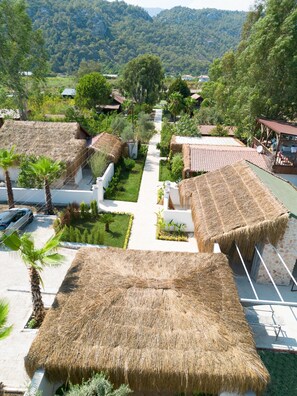 A resort with thatched-roof huts, a central pathway, and lush greenery. - Alicra Hotel Çıralı (Kemer)