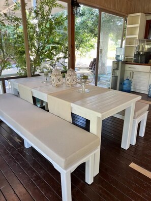 A dining area with a white table and benches, surrounded by large windows and a view of greenery. - Alicra Hotel Çıralı (Kemer)