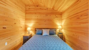 A wooden-paneled room with a bed, two bedside tables, and two lamps. - Seawall Retreat! Close to Ocean & Acadia! (Southwest Harbor)