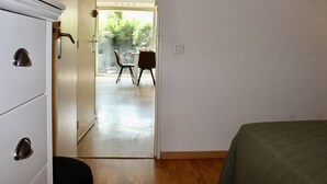 A room with a bed, a wardrobe, and a door leading to a balcony with a table and chairs. - Garden-Level 2-Room Apartment, 100m from Beach, A/C, Terrace, Free Parking (Villeneuve-Loubet)