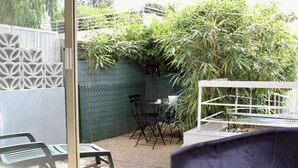 A patio area with a table and chairs, a small garden, and a decorative fence. - Garden-Level 2-Room Apartment, 100m from Beach, A/C, Terrace, Free Parking (Villeneuve-Loubet)