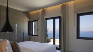 Un dormitorio moderno con una cama grande, vista al mar a través de un ventanal corredera y una lámpara colgante.