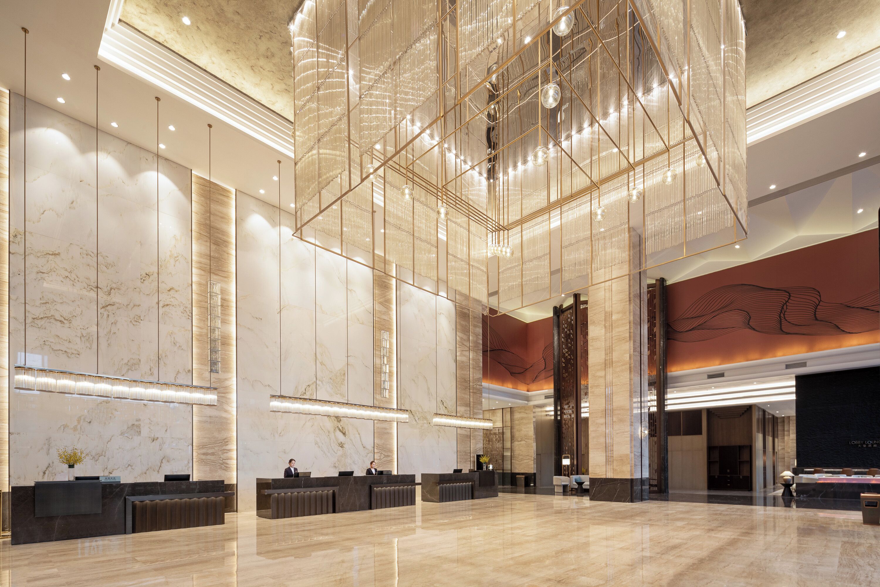 A spacious lobby with a high ceiling, marble walls, and a reception desk area.